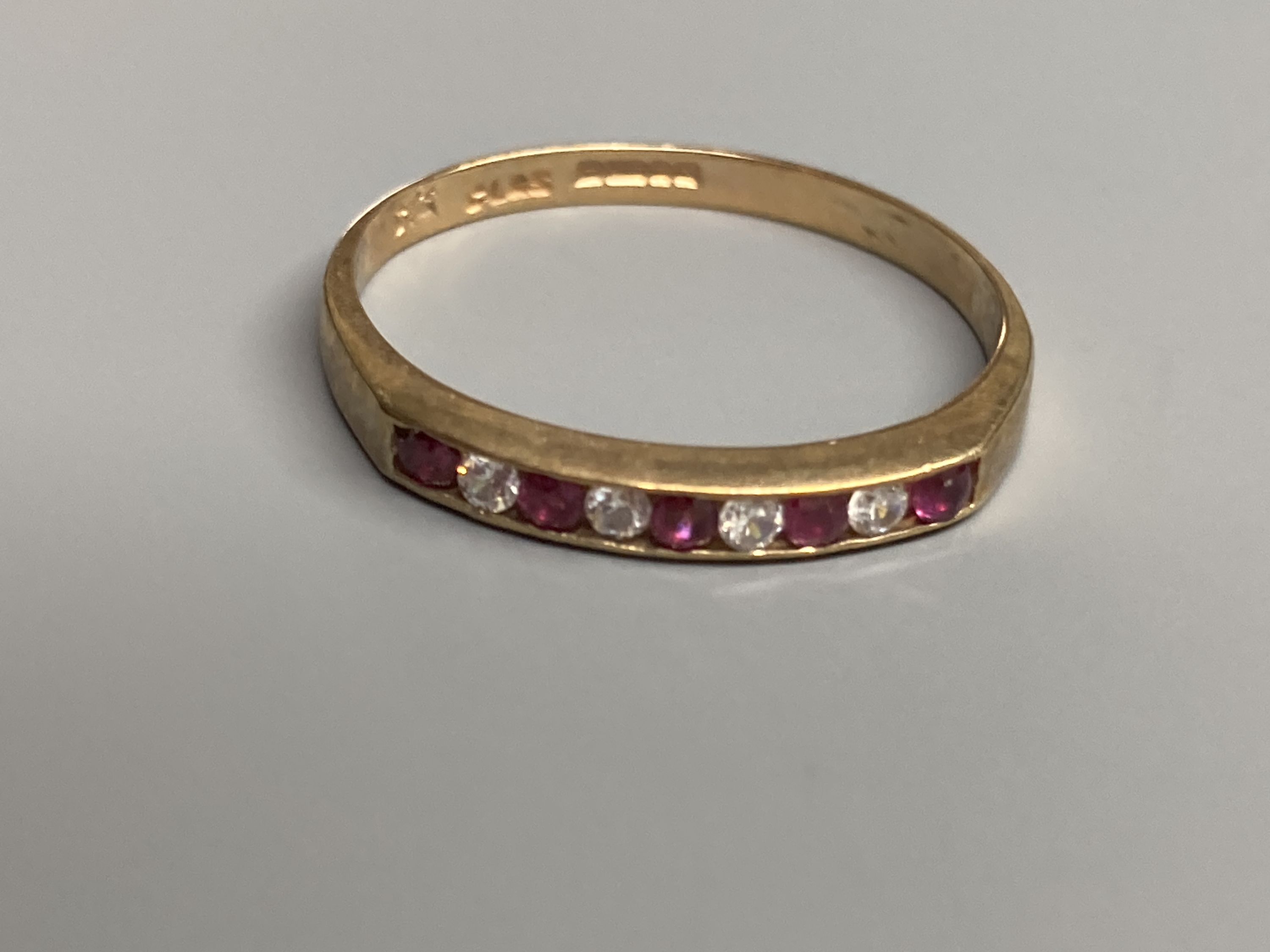 A modern 9ct gold, ruby and diamond set half hoop ring and a similar amethyst ring and two other 9ct gold gem set rings
